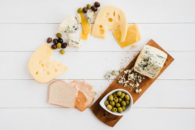 Free Photo various type of delicious cheese with bread and olives on white table