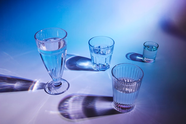 Various type of glasses with drinks on blue background