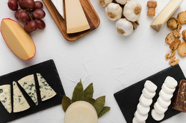 Various types of cheese with tasty grapes and ingredient on white background