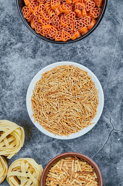 Various types of dry pasta on the marble table.