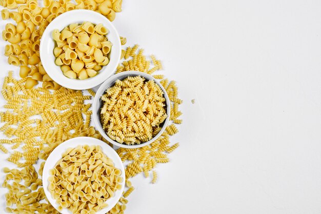 Various uncooked pasta bowls on white