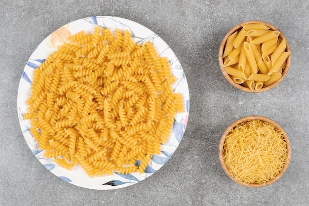 Free photo various uncooked pasta on marble surface