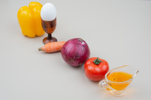 Various vegetables with egg and oil on white.