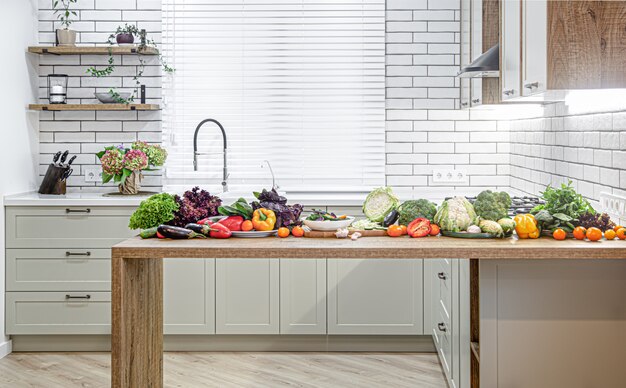 Various vegetables on a wooden table against the background of a modern kitchen interior.