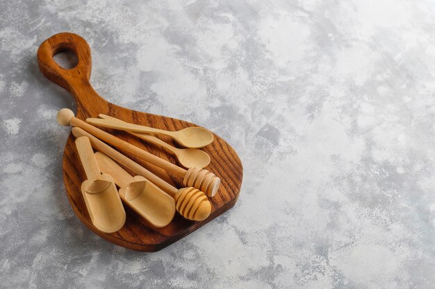 Various wooden spoons with handmade wooden cutting board on grey concrete 