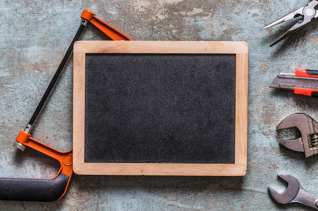 Various worktools and blank slate on old wooden desk