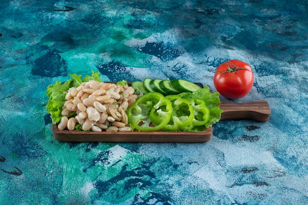 Variously vegetables and beans on a board on the blue table. 