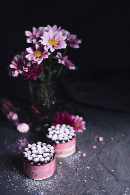 Free Photo vase flower with blackcurrant cheese cake with sugar powder dusting