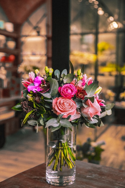 Vase with flower composition on wooden table mix roses