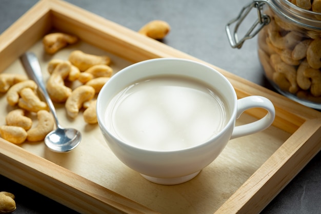 Vegan cashew milk in glass with cashews nuts on dark background