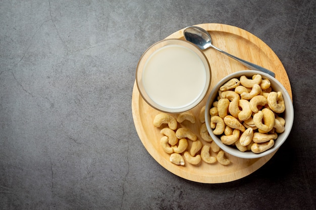 Vegan cashew milk in glass with cashews nuts on dark background