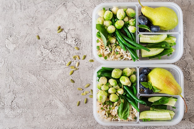 Free photo vegan green meal prep containers with  rice, green beans,  brusselssprouts, cucumber and fruits. dinner in lunch box.