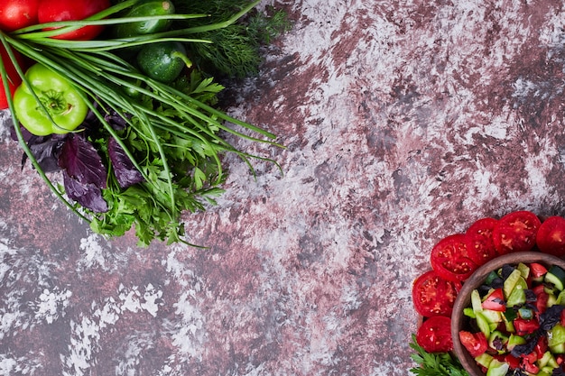 Vegetable mix isolated on a piece of marble with a cup of salad aside in both corners.