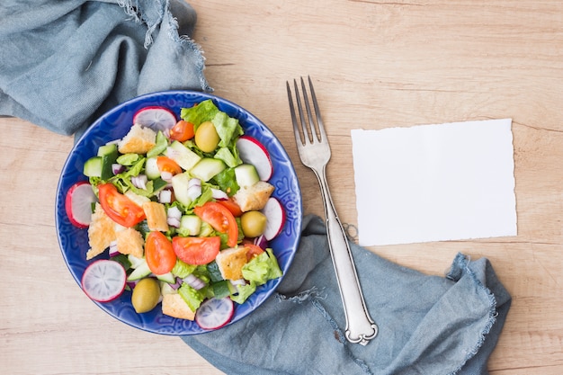 Vegetable salad in bowl with blank paper 