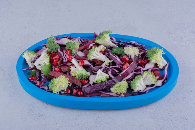 Free photo vegetable salad mixed with pomegranate arils on marble background.