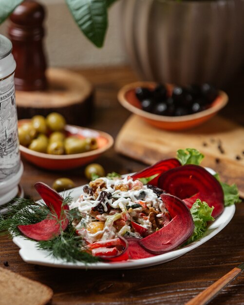 Vegetable salad of prune, carrot, tomato, walnut garnished with beets slices