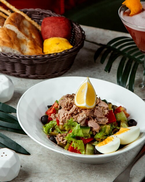 Vegetable salad topped with meat and lemon