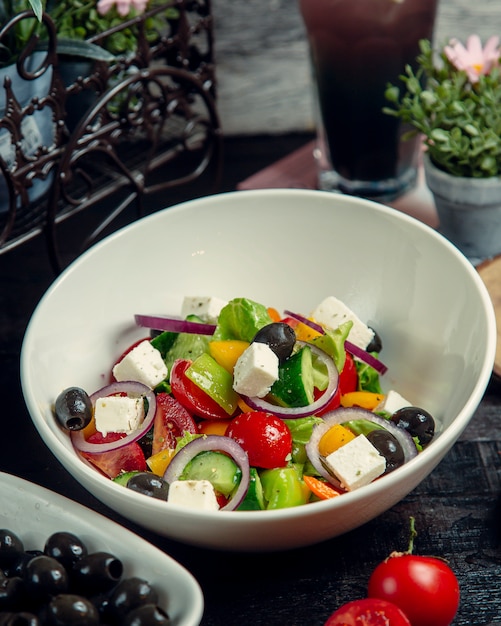 Free photo vegetable salad topped with olives and cheese