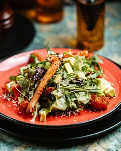 vegetable salad with fried ships greens avocado bell pepper lettuce and bread sticks on plate