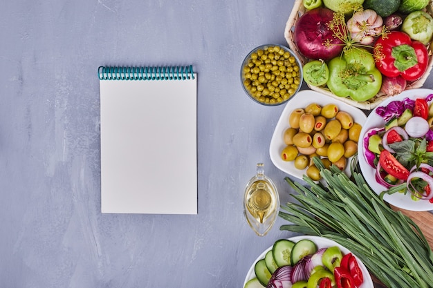 Free photo vegetable salad with sliced and chopped foods and a recipe book aside.