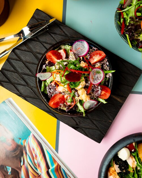 Vegetable salad with tomatoes on a black board.