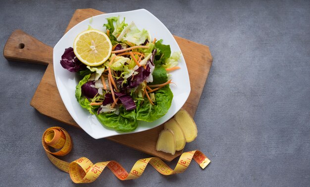 Vegetable salad on wooden board with measuring tape on table