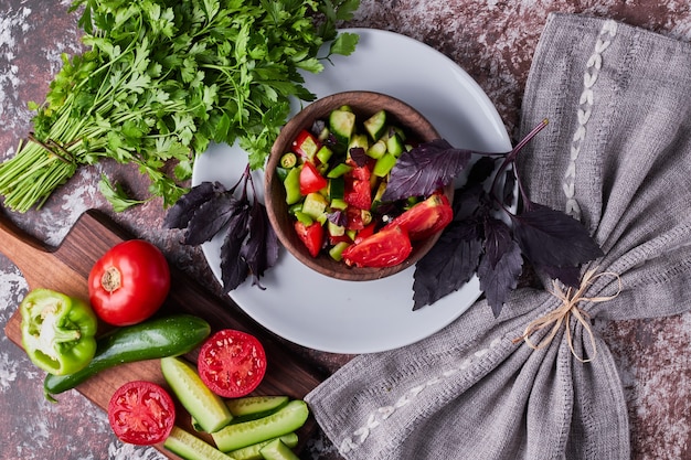 Vegetable salad in a wooden cup served with herbs, top view