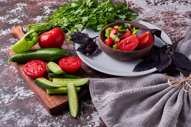 Vegetable salad in a wooden cup served with herbs.