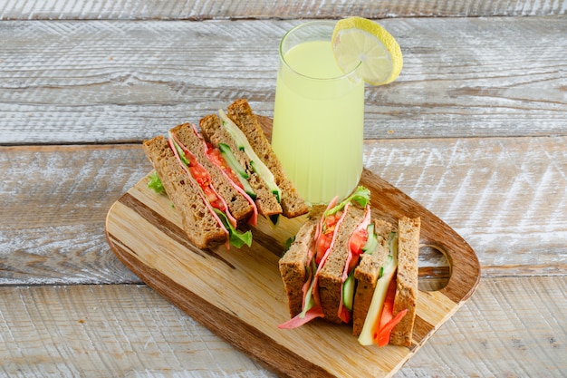 Free Photo vegetable sandwich with cheese, ham, lemonade on wooden and cutting board, high angle view.