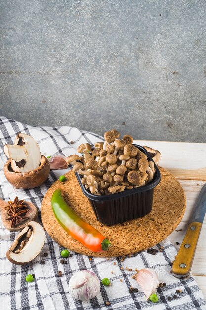 Vegetable; spices; cork coaster and knife on wooden table