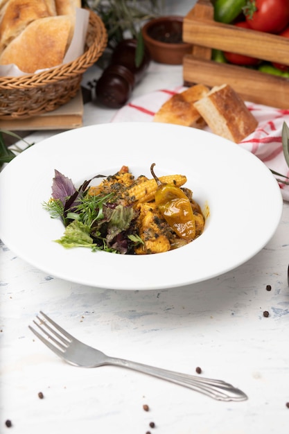 Vegetable stew with meat, corn pieces, chili pepper and vegetables, basilic, parsley in white plate. 