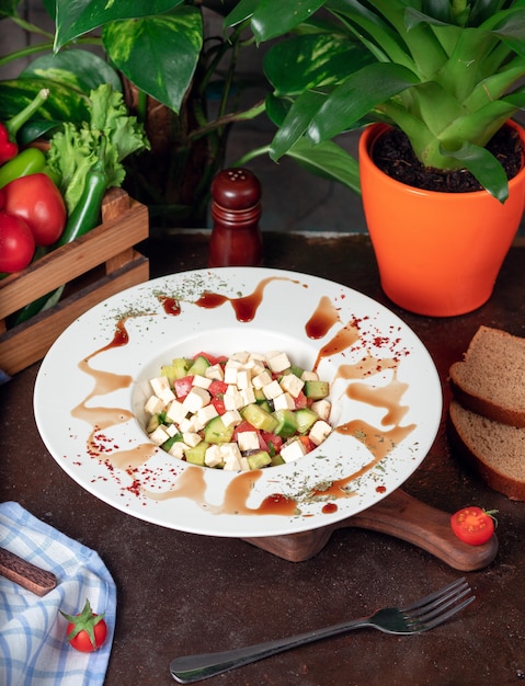 Vegetable, tomatoes, cucumber, roka salad. salad with sumakh and lemon on the kitchen table inside white plate