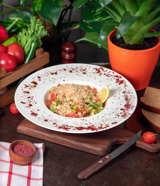 Vegetable, tomatoes, cucumber salad with crackers. salad with sumakh and lemon on the kitchen table inside white plate 