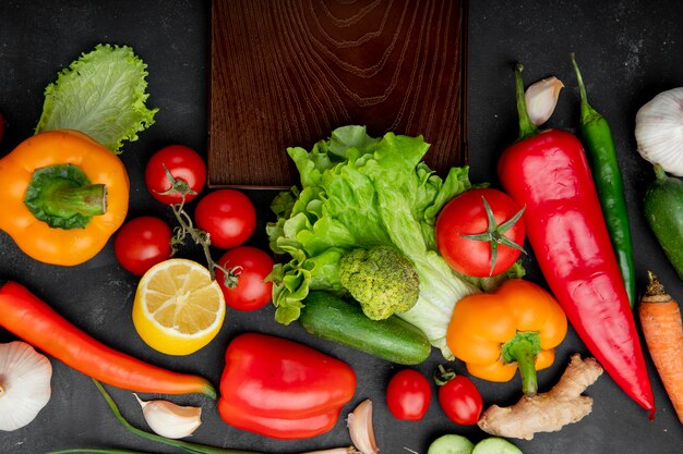  vegetables as pepper lettuce tomato and others with lemon and cutting board on black table