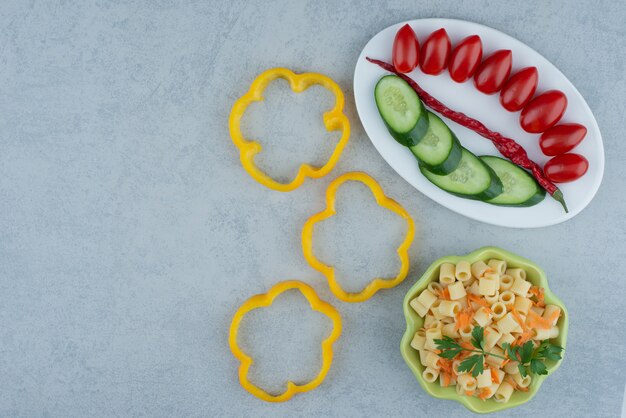 Vegetables salad on white plate with macaroni on marble background. High quality photo