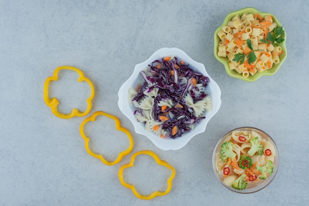 Free photo vegetables salad on white plate with macaroni on marble background. high quality photo