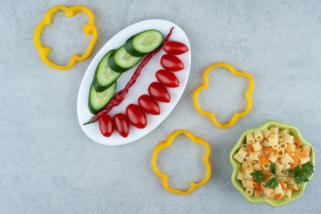 Vegetables salad on white plate with macaroni on marble background. High quality photo