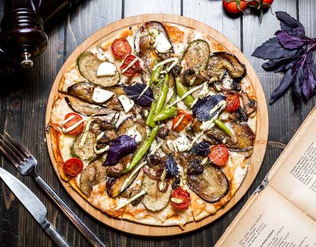 Vegetarian pizza eggplant mushroom olives tomato basil pepper cheese top view