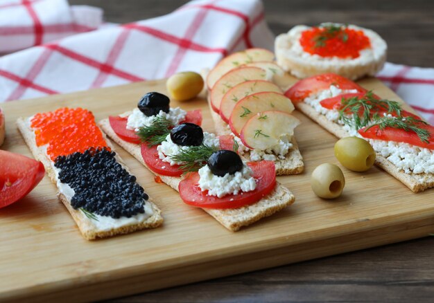 Vegeterian sandwiches with mixed foods on a wooden board.