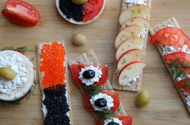 Vegeterian sandwiches with mixed foods on a wooden board.