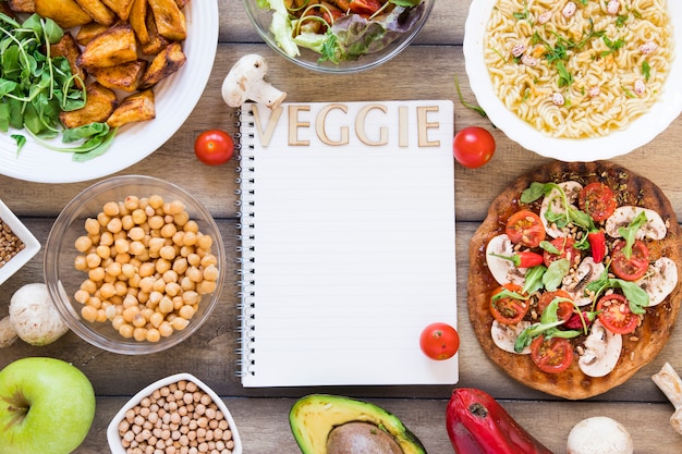 Veggie lettering on notebook surrounded by veggie food 