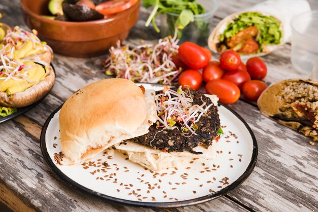 Veggie quinoa burger with sprouts and flax seeds on white plate