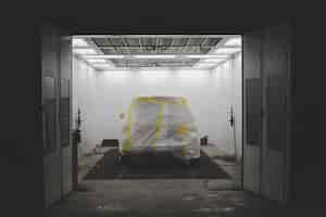 Free photo vehicle covered with a white sheet and yellow tape in a car service garage