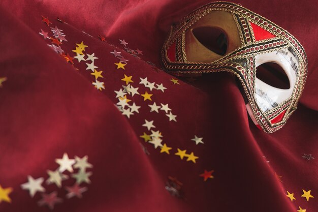 Venetian mask on a red fabric with star confetti