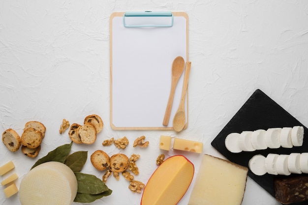 Free photo verity of cheese; bread slice; walnut; bay leaves with empty clipboard