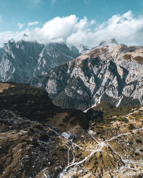 Free photo vertical aerial shot of mountains under blue sky and white clouds