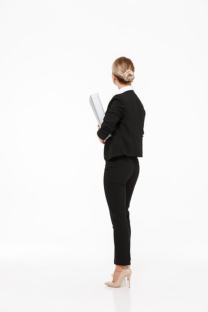 Free Photo vertical back view of blonde business woman holding big folder over white wall