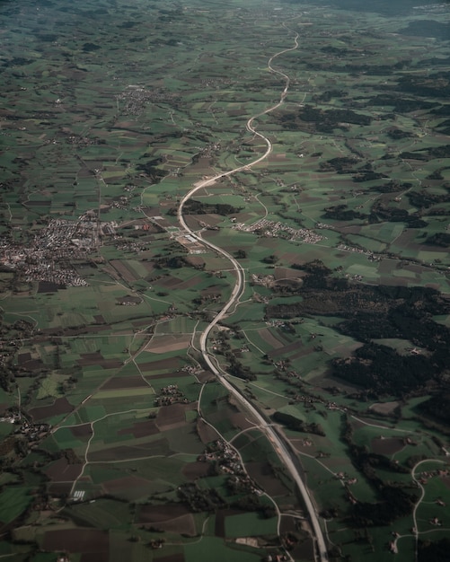 Free photo vertical bird-eye view of an endless road and green fields