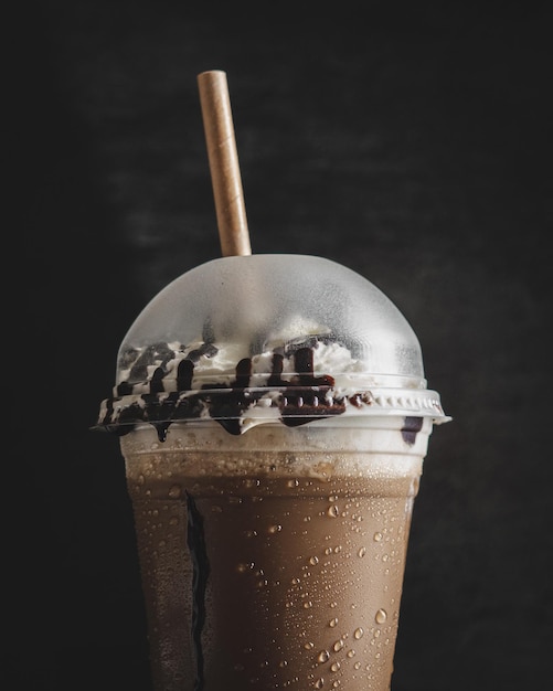 Free photo vertical closeup of a plastic cup of cold coffee with a vanilla cream