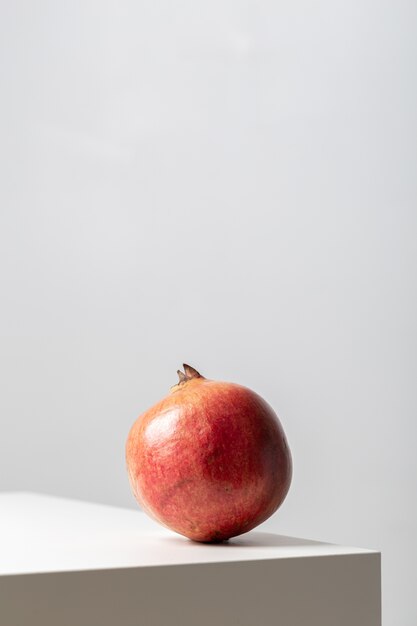 Vertical closeup of a pomegranate on the table under the lights on white